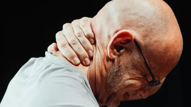 man in pain holding back of head